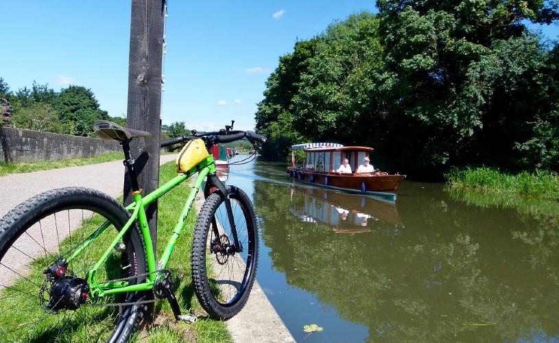 Bike by canal with a boat going past